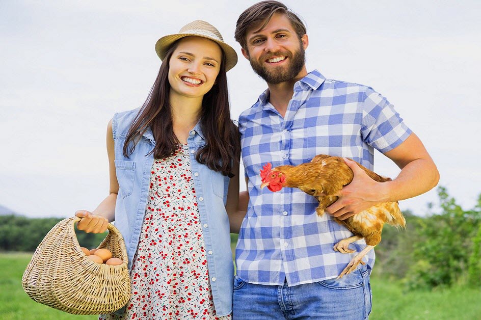 Happy farmer couple with chicken and basket of freshly collected eggs